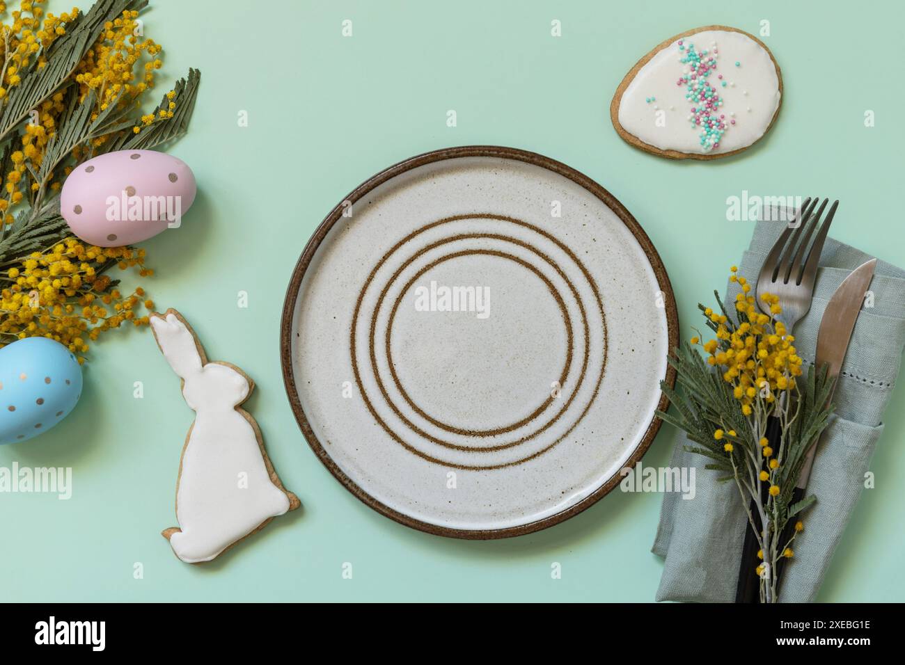 Table setting for Easter dinner with easter eggs and mimosa on a pastel background. Stock Photo