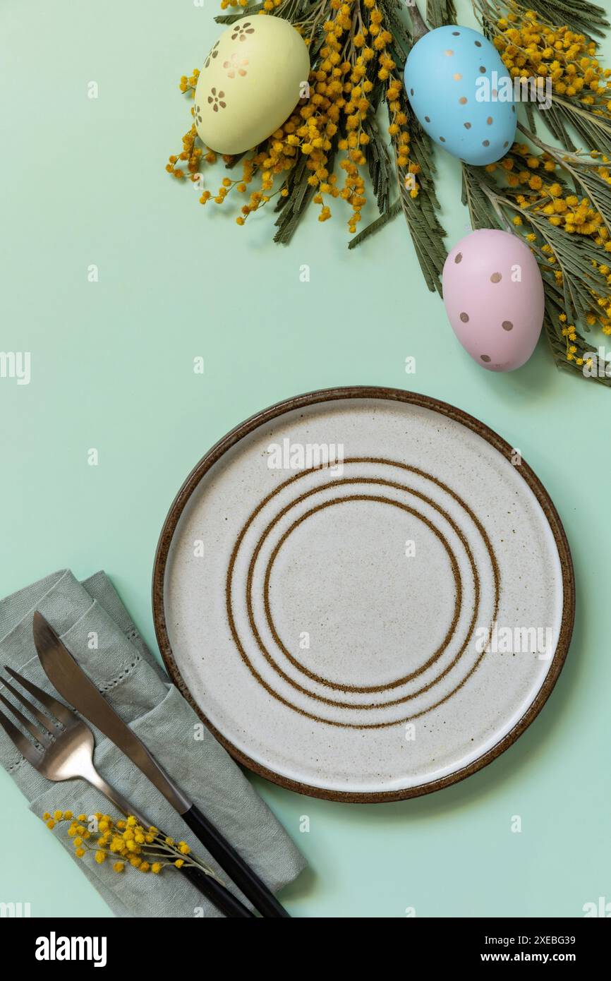 Table setting for Easter dinner with easter eggs and mimosa on a pastel background. Stock Photo