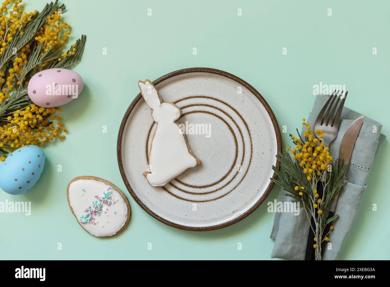 Table setting for Easter dinner with easter eggs and mimosa on a pastel background. Stock Photo