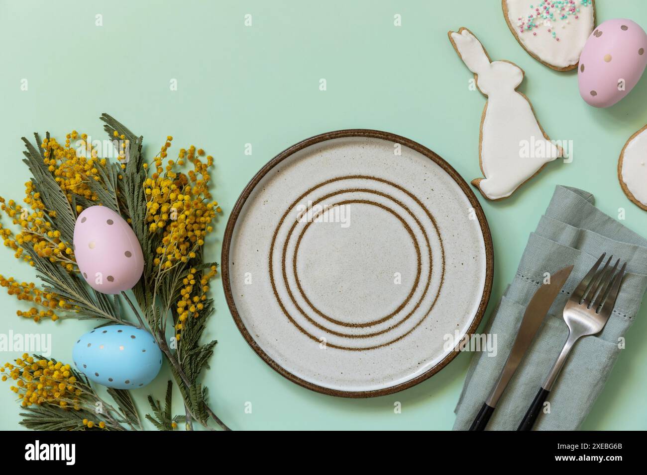 Table setting for Easter dinner with easter eggs and mimosa on a pastel background. Stock Photo