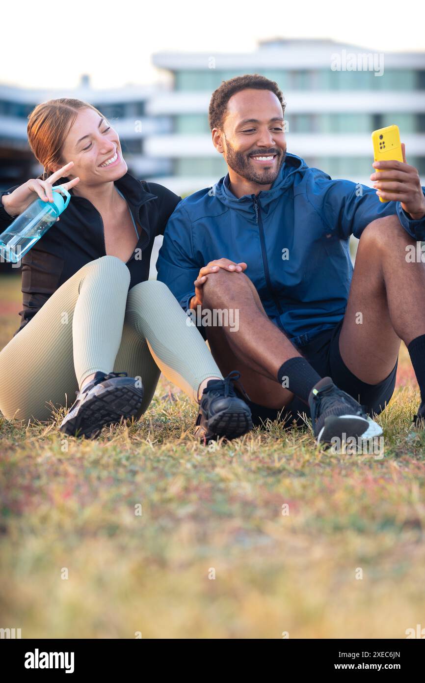 Young couple taking a selfie with their smartphone ready to exercise.Vertical Stock Photo