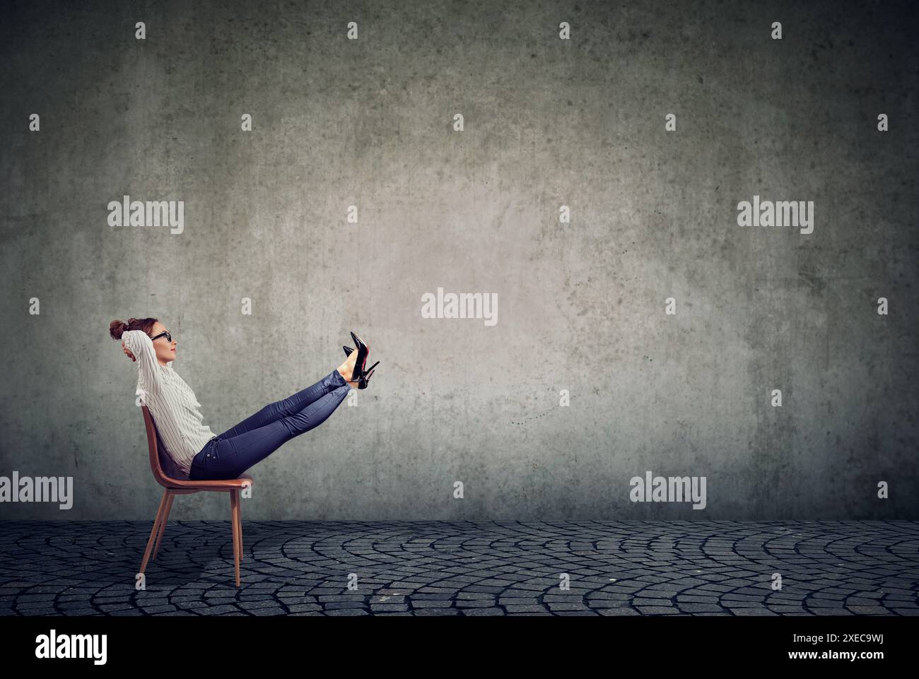 Young business woman sitting in office chair with her legs raised up daydreaming Stock Photo