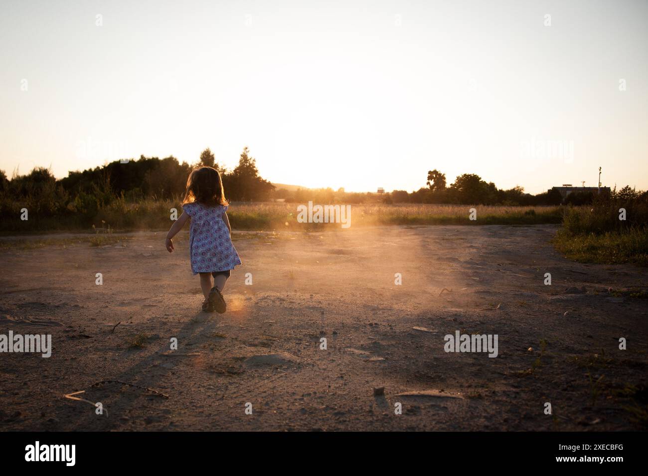 A little girl playing outside at sunset - a symbol of freedom, joy and childhood Stock Photo