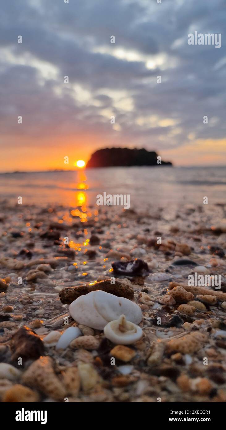 The sun sets gracefully over the calm ocean, casting a warm glow on the ...