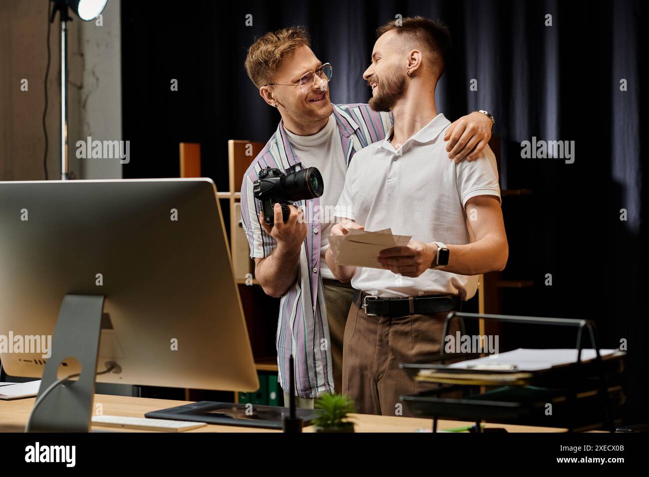 Two men collaborate on computer projects in modern office setting. Stock Photo