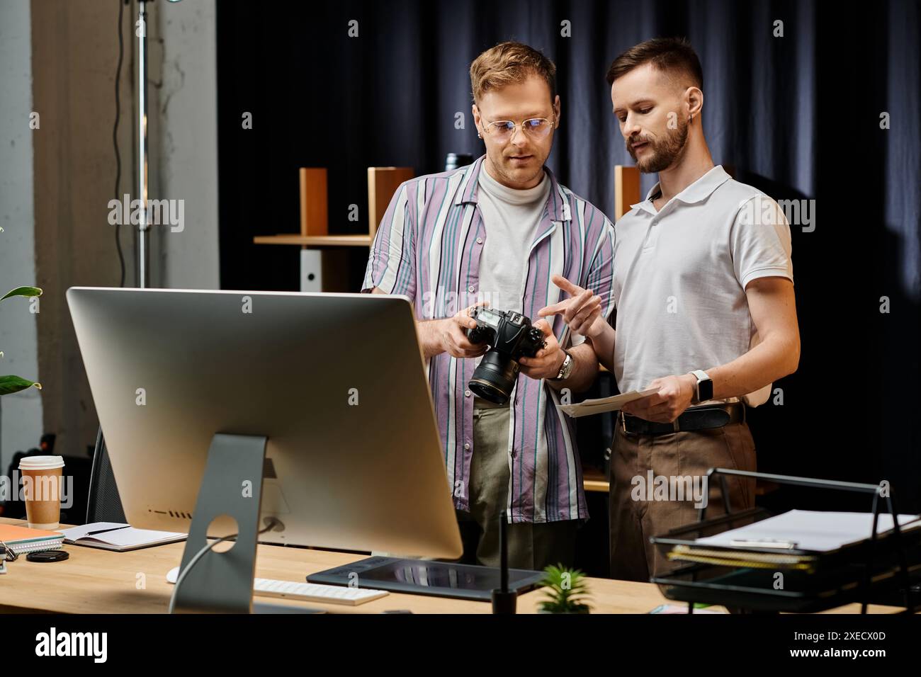 Two men engrossed in a computer screen, collaborating in a cozy office setting. Stock Photo