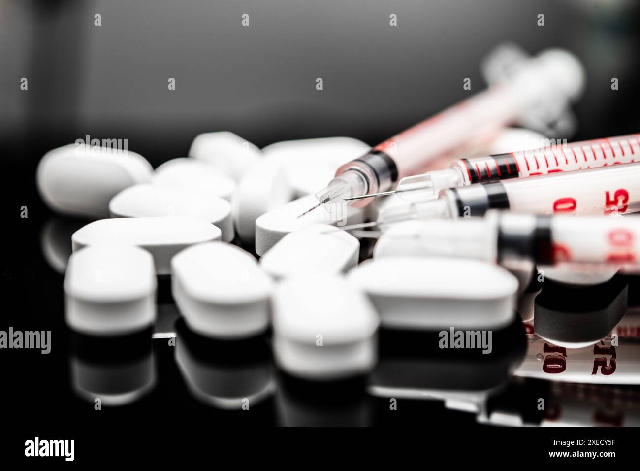 Close-up View of White Medication Pills and Medical Syringes on a Reflective Surface, prescription drugs, prescription opioids, fentanyl Stock Photo