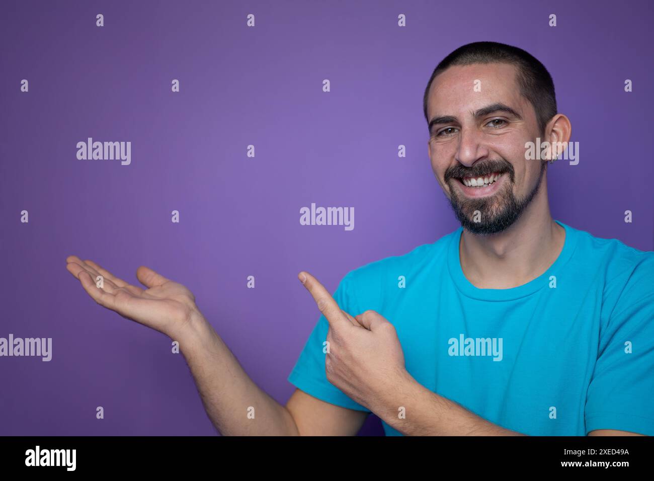 Young man pointing empty space using hands and fingers, isolated over violet background Stock Photo