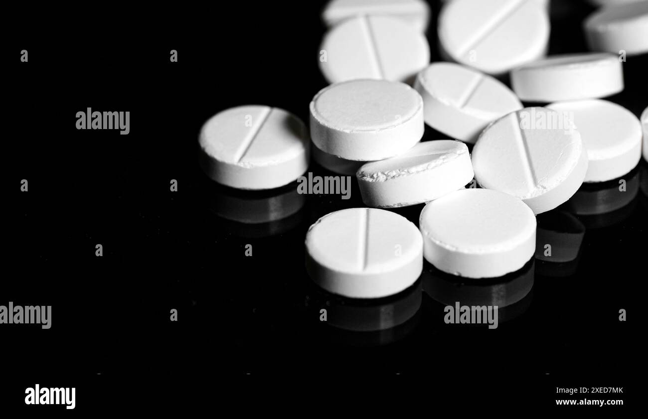 Close up of white painkiller tablet on a reflective black backgr Stock Photo