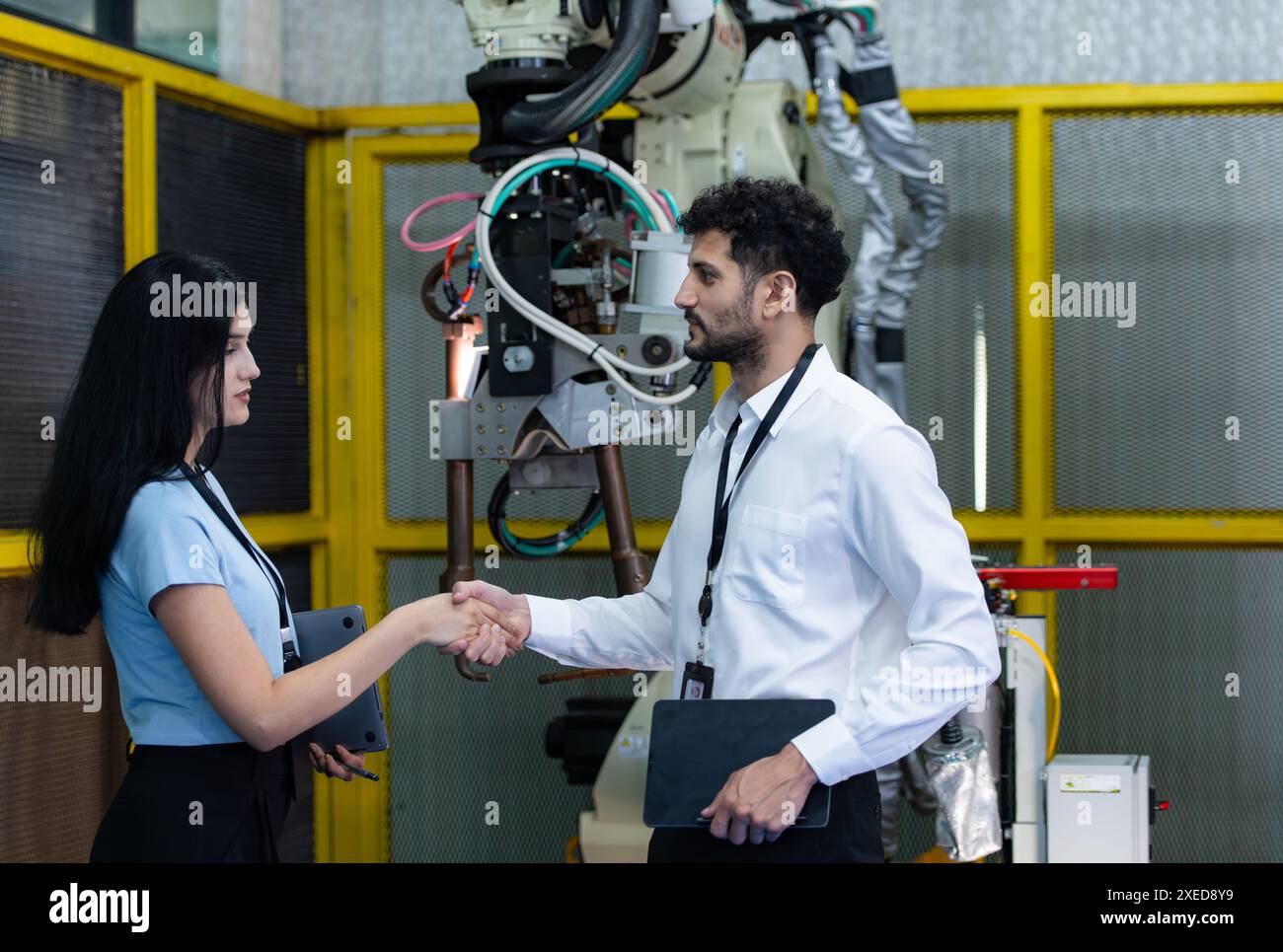 Business partner shaking hands while inspecting on industrial machine in factory Stock Photo