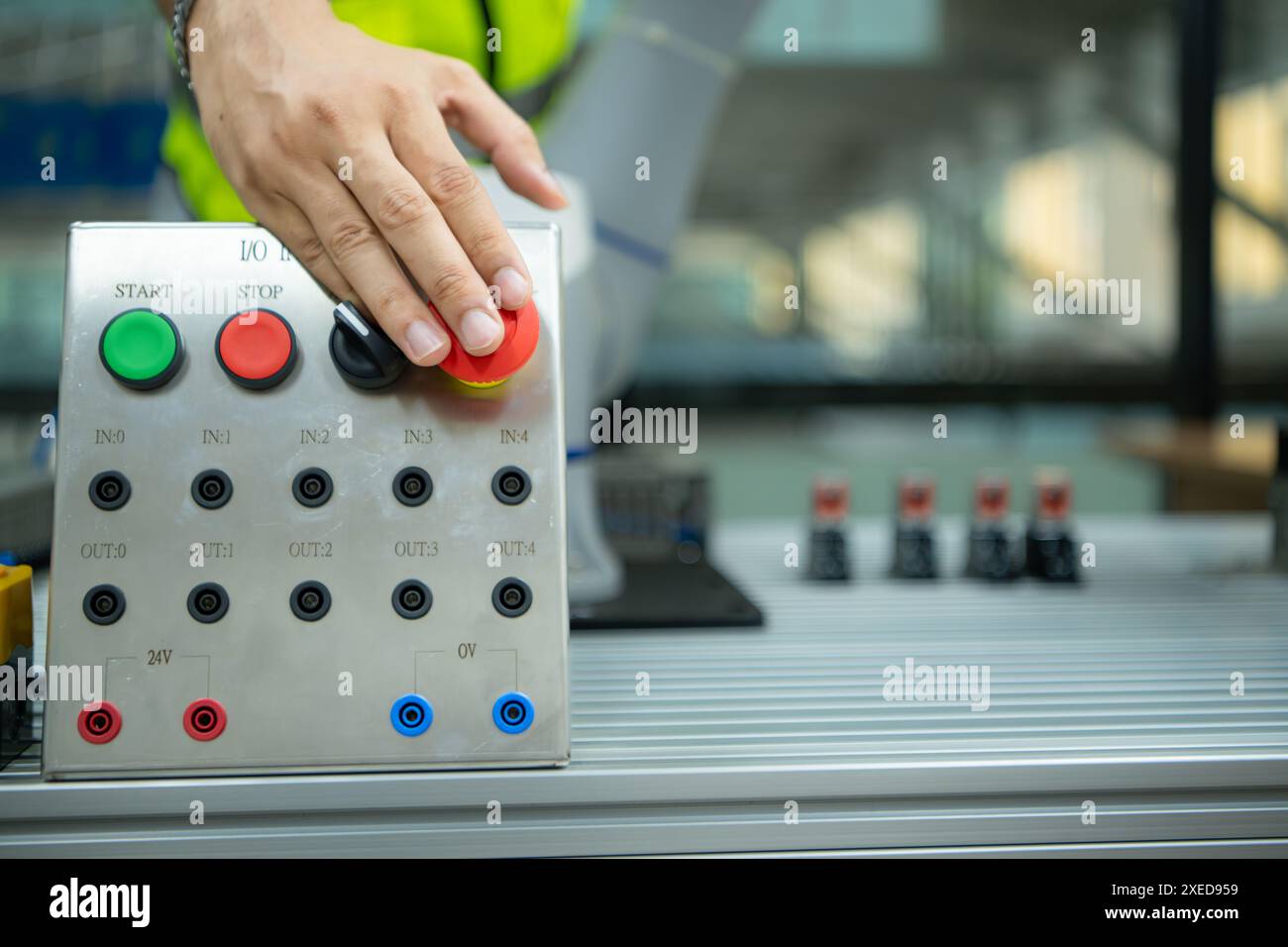 Close-up of hand pressing the stop button on the control panel of an industrial machine. Stock Photo