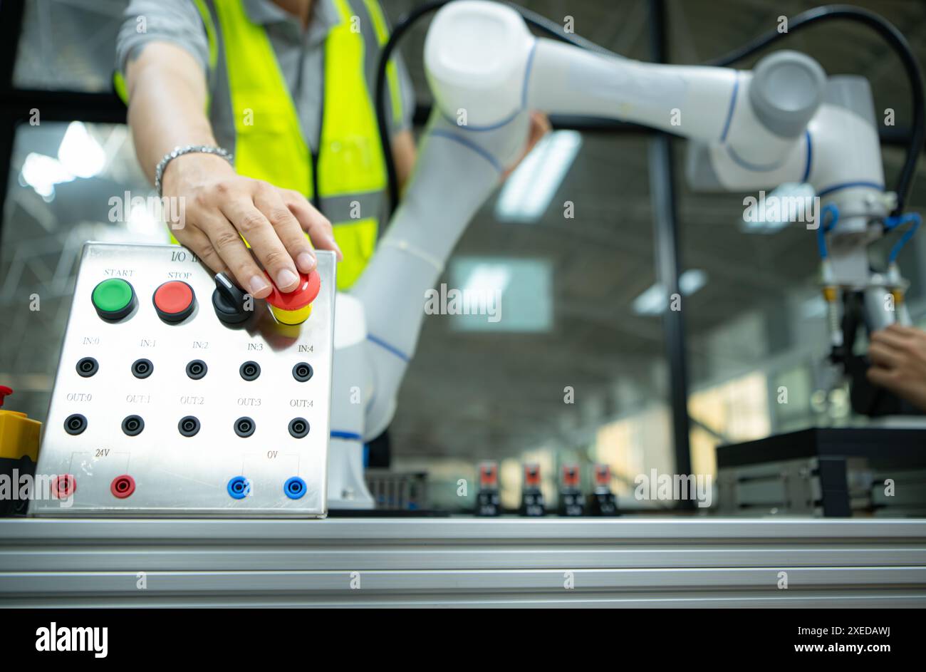 Close-up of hand pressing the stop button on the control panel of an industrial machine. Stock Photo