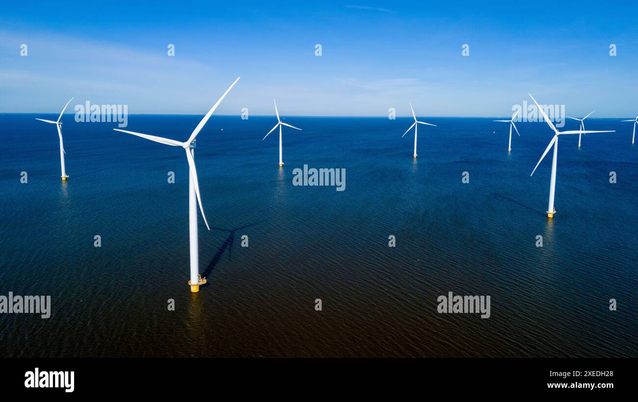 A group of wind turbines elegantly spin in the ocean off the coast of ...