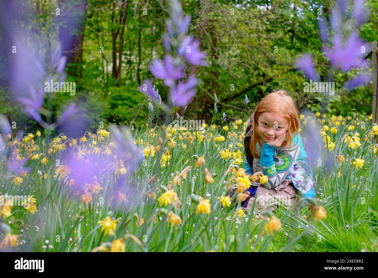 This image captures a young red-haired girl crouching among a myriad of ...