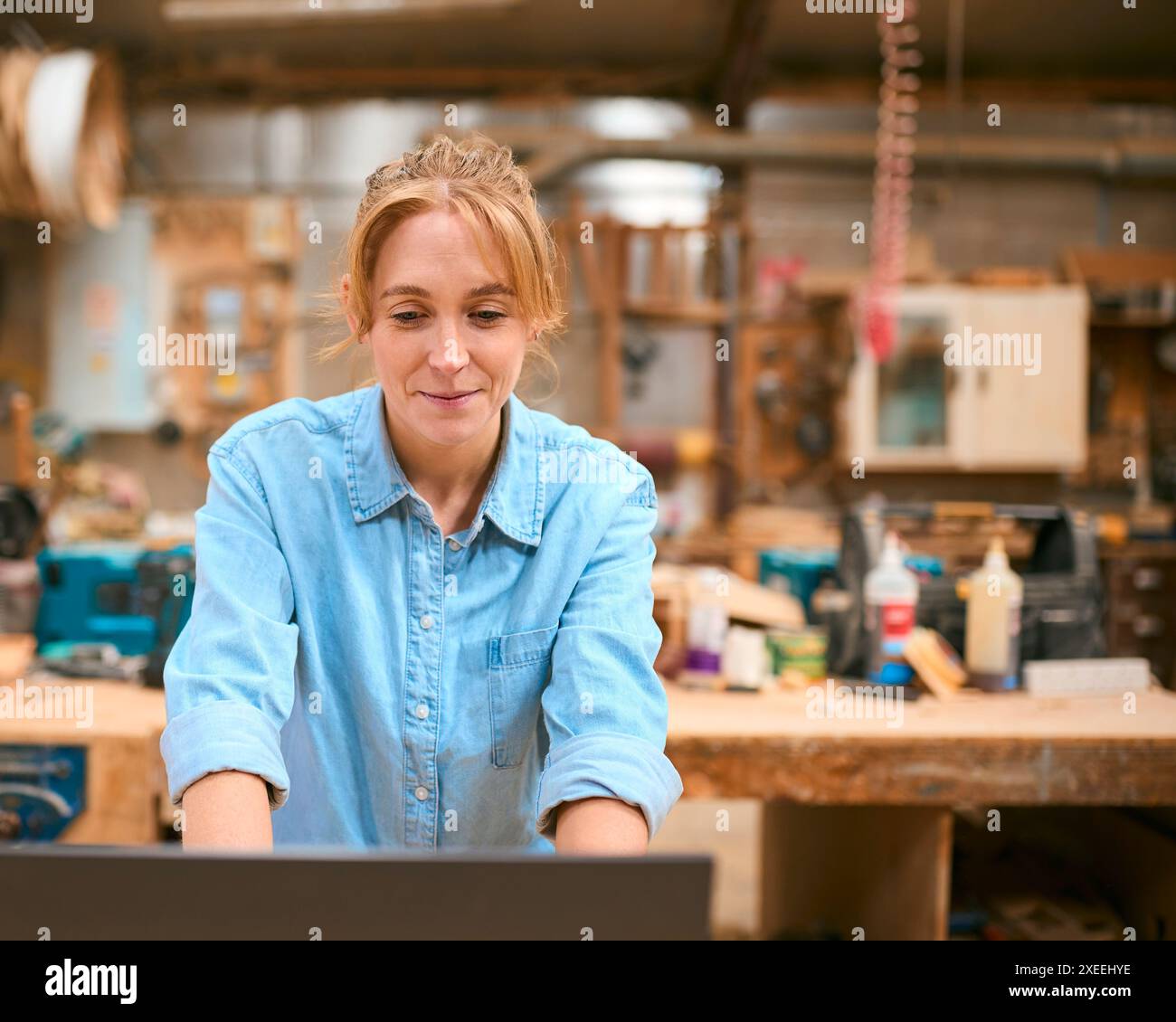 Female Carpenter Working In Woodwork Workshop Using Laptop Stock Photo