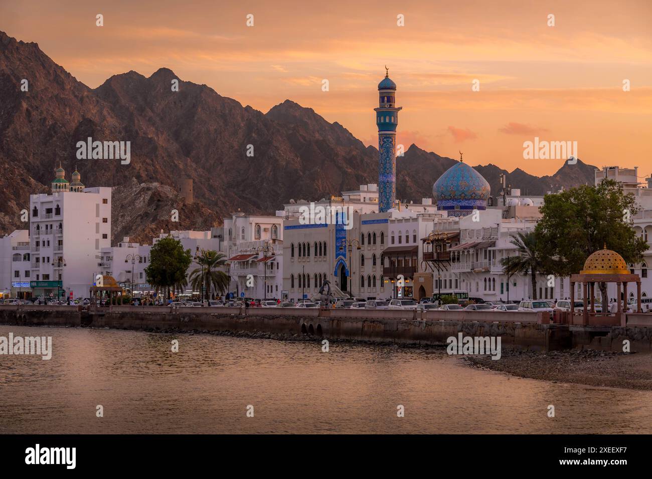 The beautiful panorama of Mutrah Corniche in Muscat, the capital of Oman, with Masjid Al Rasool Al A'dham mosque, people on the promenade, at sunset. Stock Photo