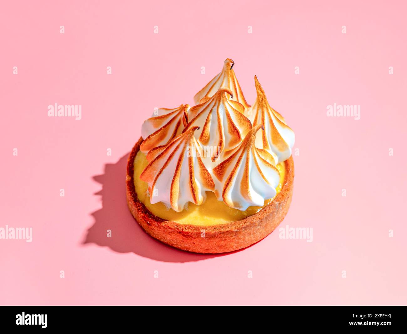 Lemon tart with burnt meringue, pink background Stock Photo
