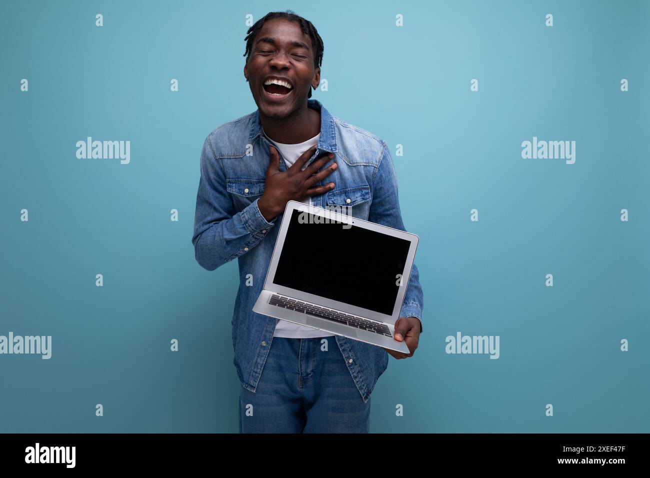 Successful freelancer american man with dreadlocks in denim jacket works remotely using laptop Stock Photo