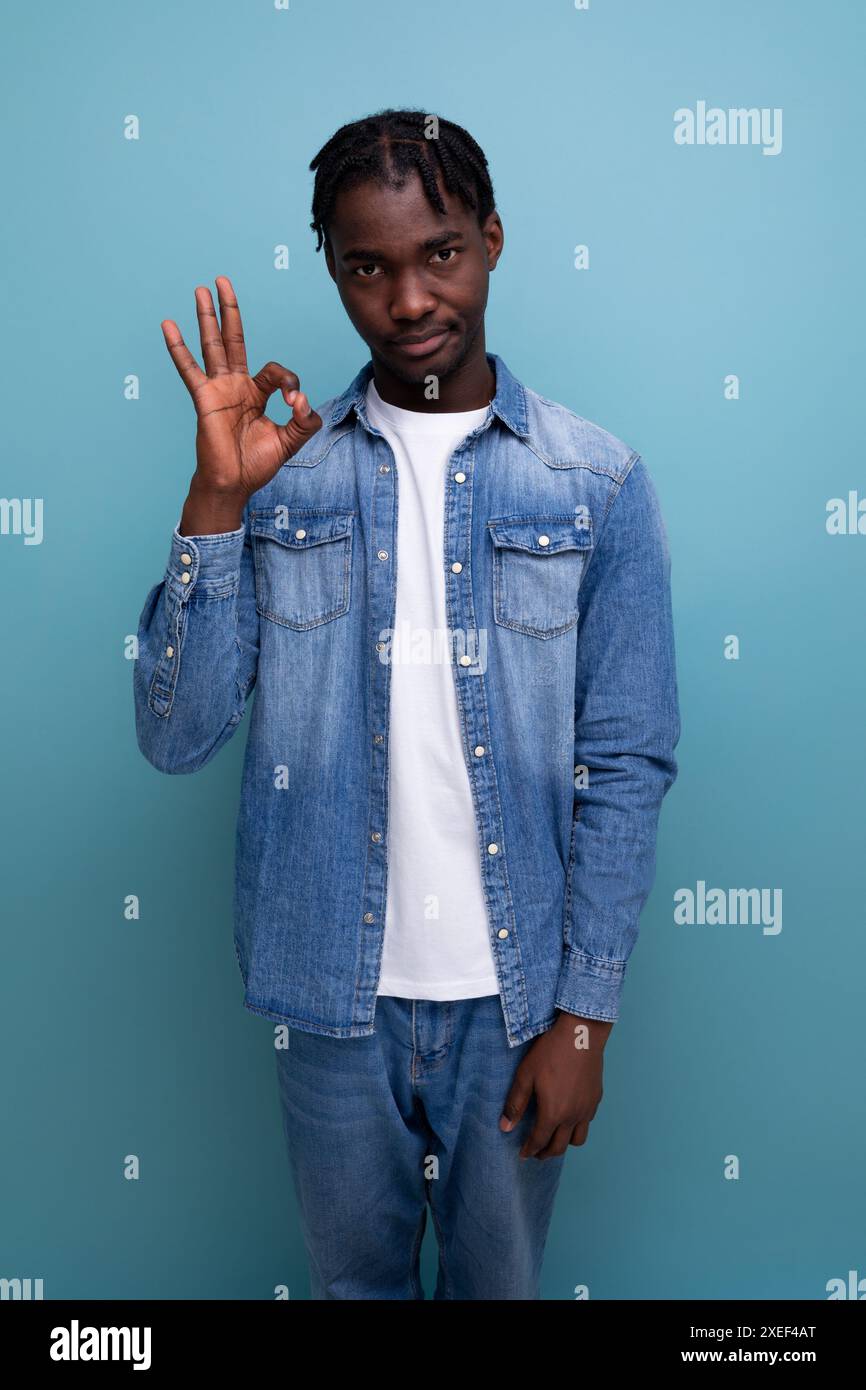 Portrait of a young cheerful american man with dreadlocks in a denim jacket showing that everything is ok Stock Photo