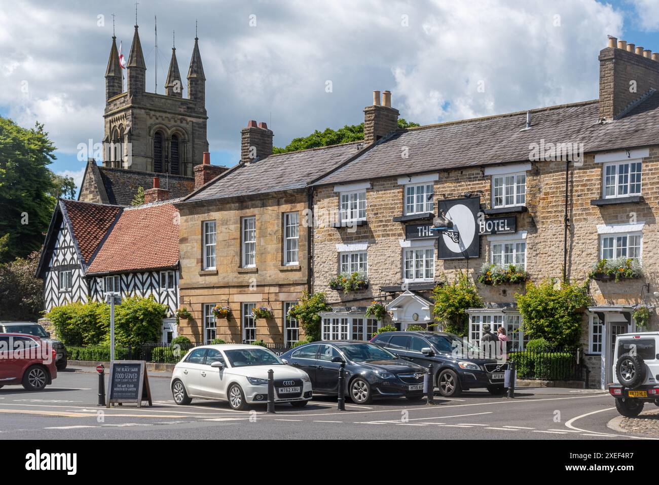 View of the market place in Helmsley town centre, North Yorkshire, England, UK, with the Black Swan Hotel and church tower Stock Photo