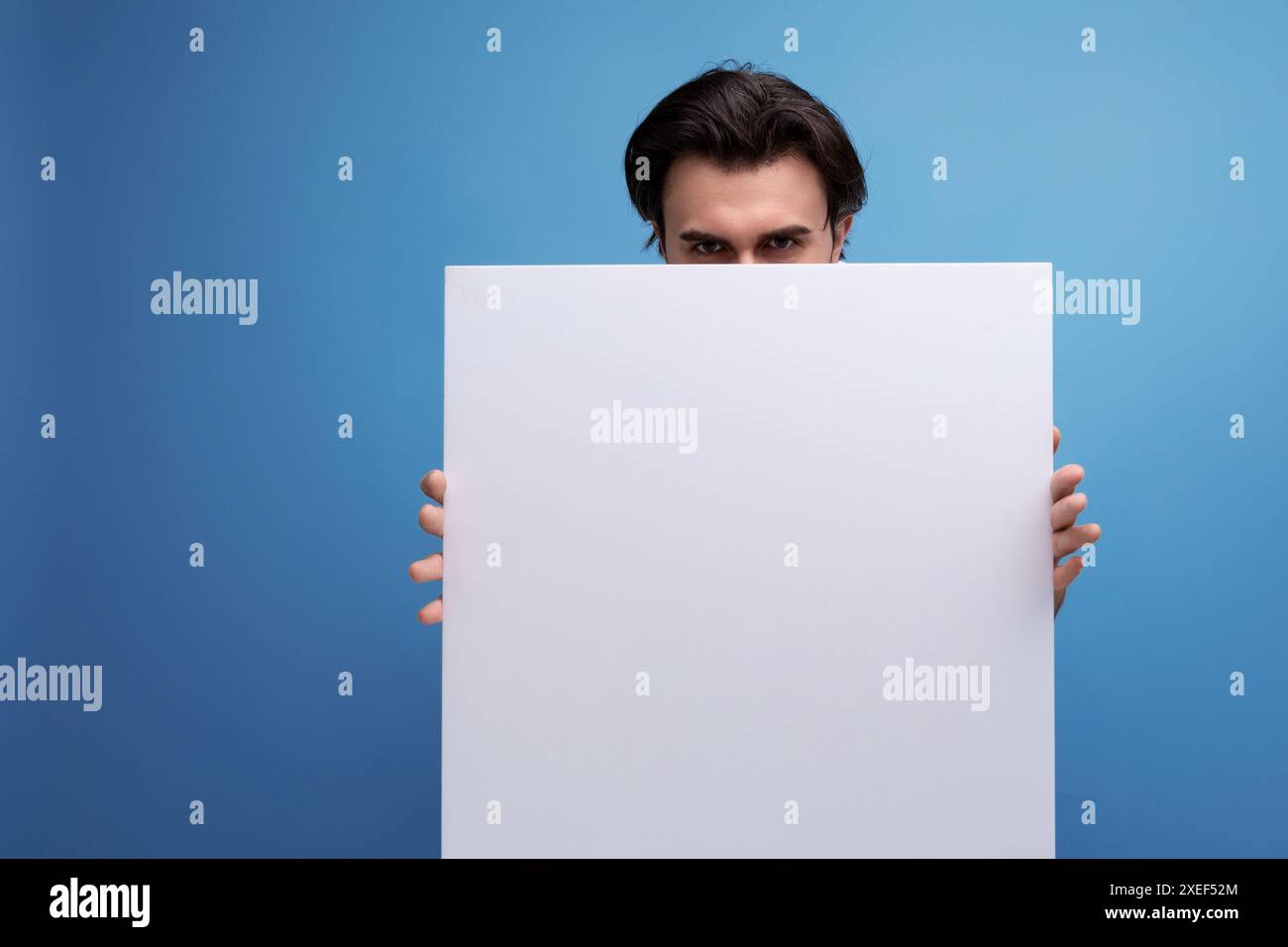 Young brutal brunette guy with poster mockup Stock Photo