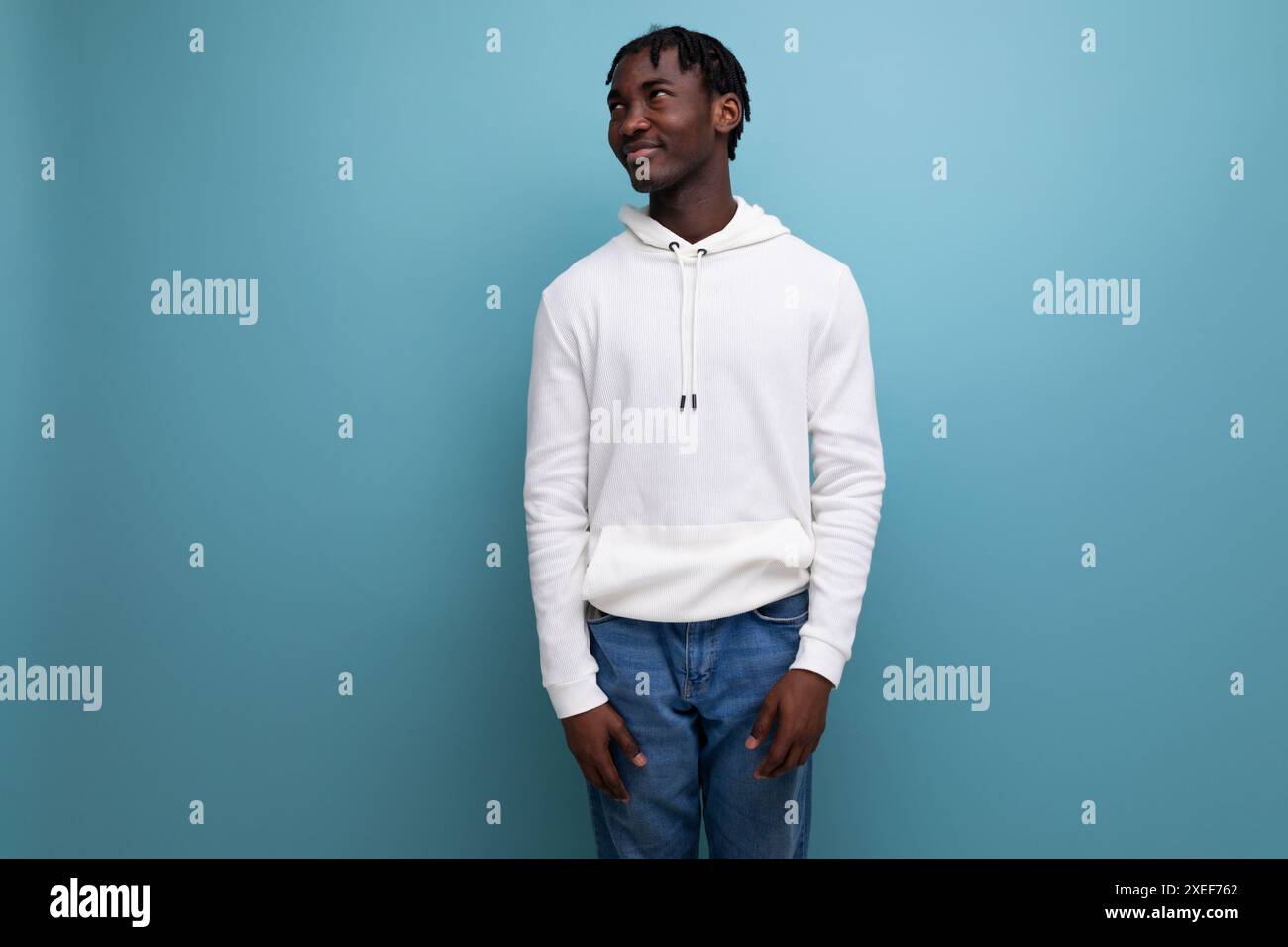 Active american young man with dreadlocks in a white sweater inspired on a blue background Stock Photo