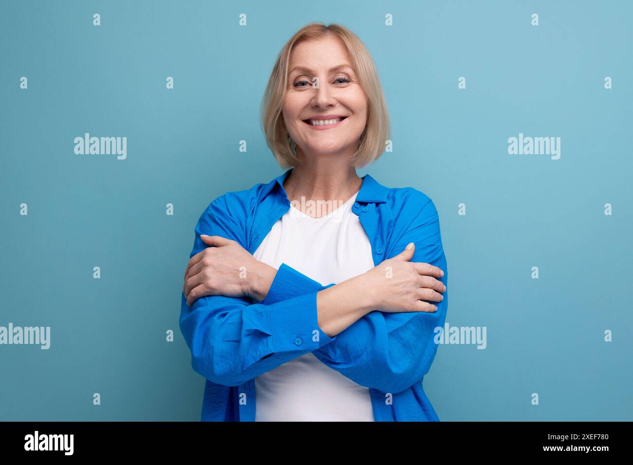 Energetic 50s woman in an attractive look on a blue background with copy space Stock Photo