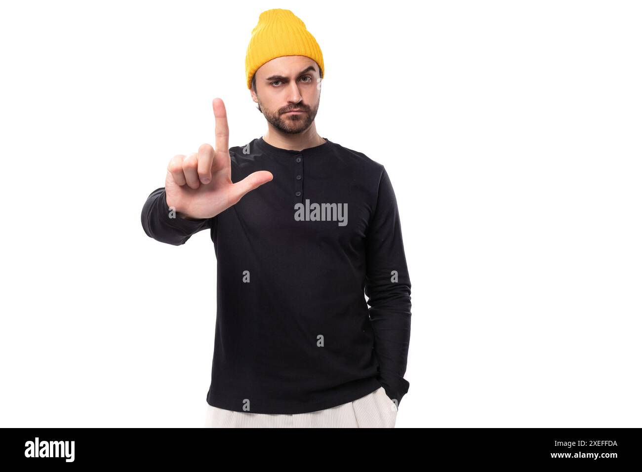 Young brunette confident male model with a beard dressed in a black jacket and a yellow hat Stock Photo