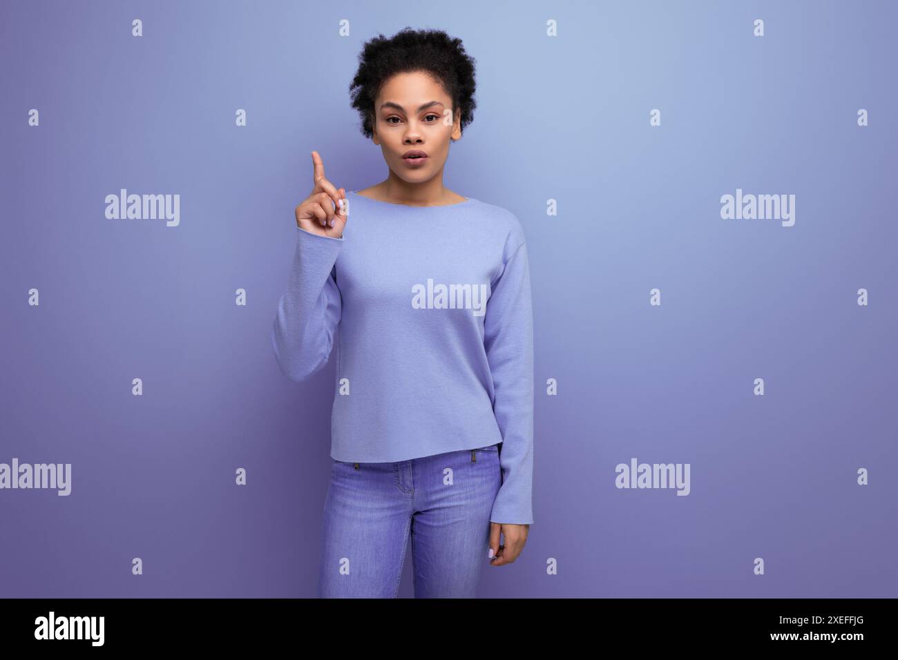 Serious young latino 20s woman with black hair tied up in a bun shows the idea with her finger Stock Photo