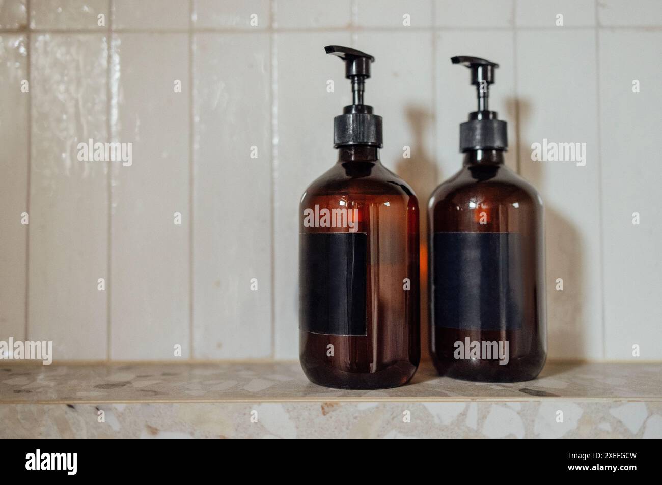 Close-up layouts with brown plastic bottles with dispensers in the bathroom. Mock-ups of shampoo or gel tubes with black empty l Stock Photo