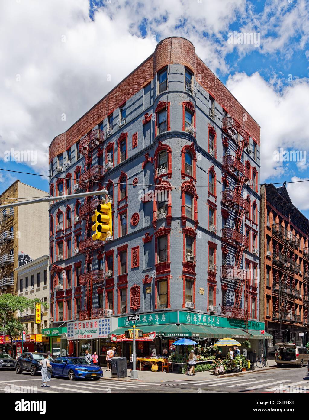 NYC Chinatown: 218 Grand Street, a seven-story walk-up apartment building with turreted corner; brick painted grey with red terra cotta decoration. Stock Photo