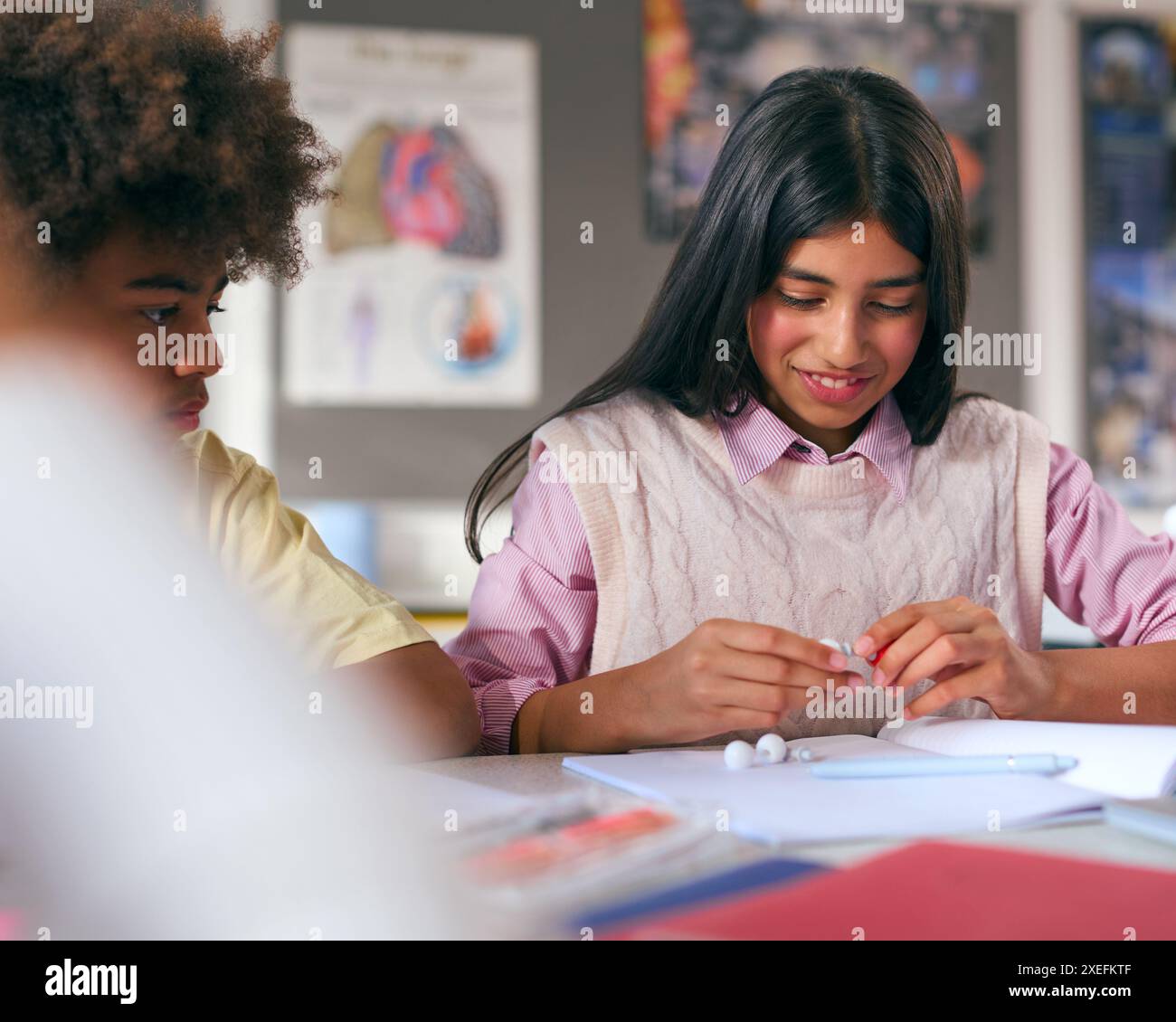 Secondary Or High School Students Sitting At Table In Science Class With Model Of Atom Or Molecule Stock Photo