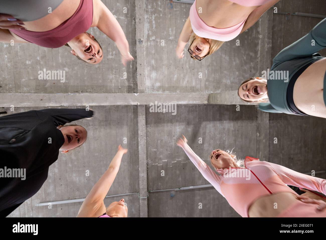 Underneath Perspective of Women in Sportswear Forming a Circle in a Concrete Space Stock Photo