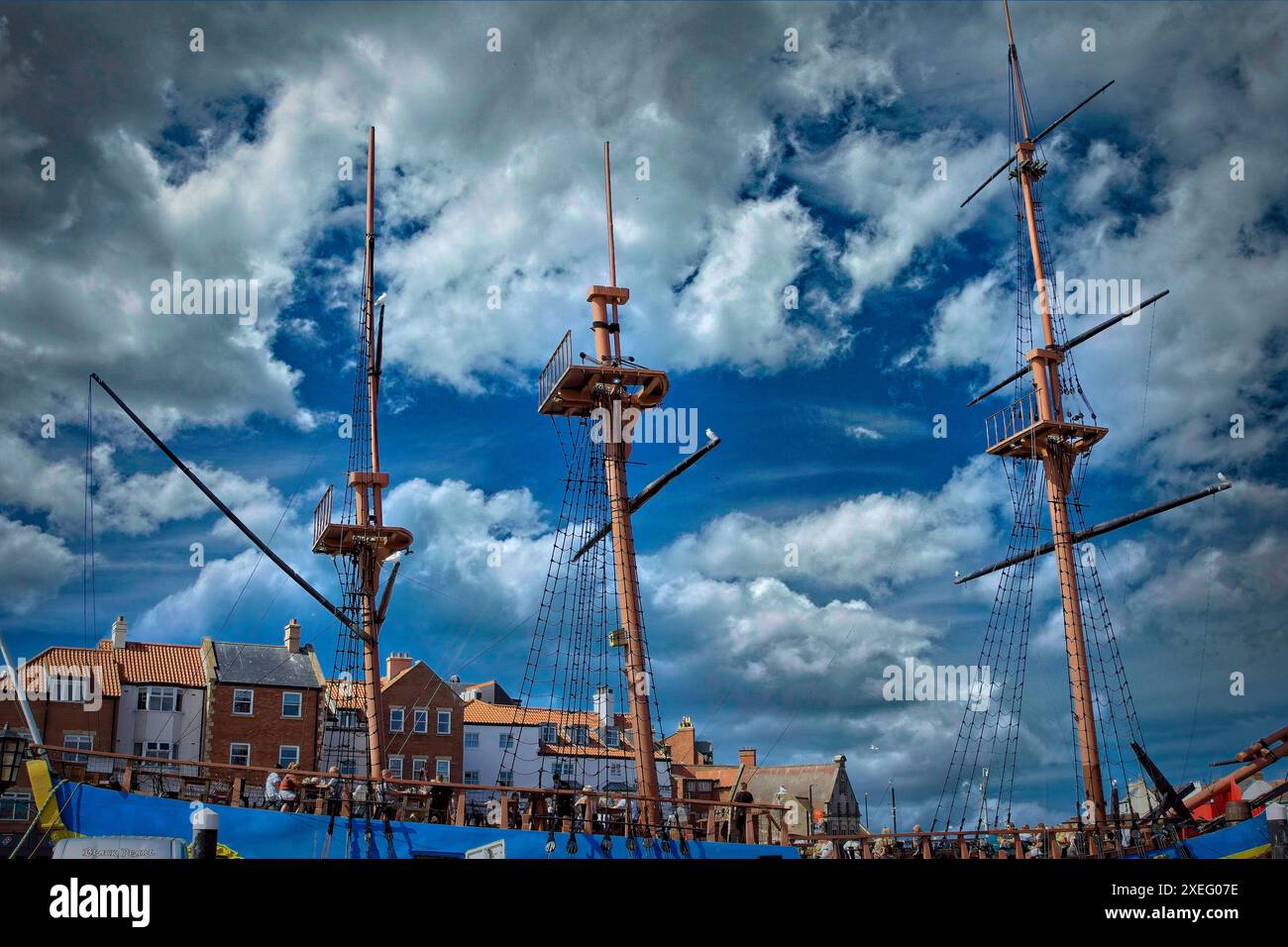 Tall ship masts against a dramatic cloudy sky in a coastal town Stock ...