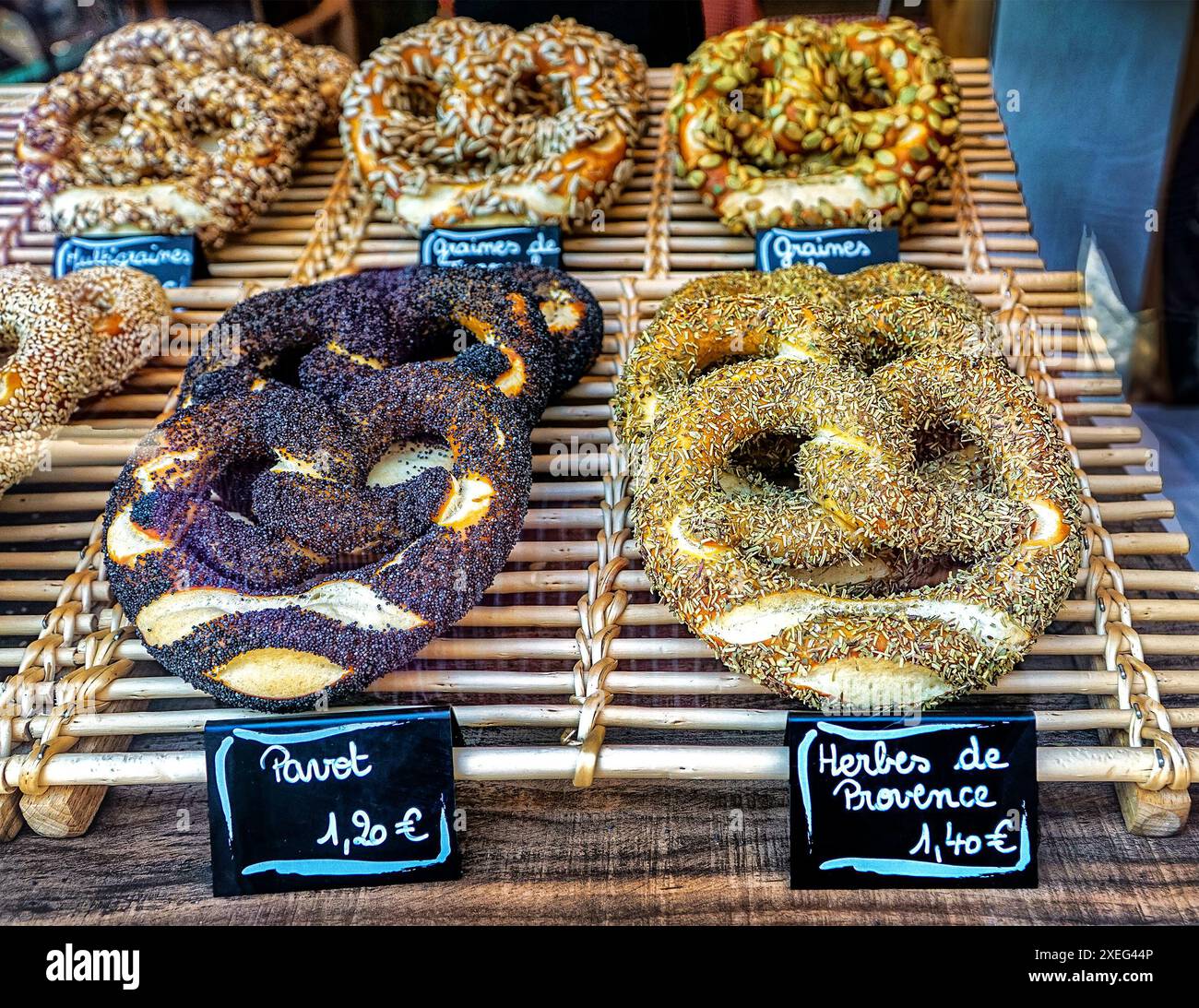 Seasoned specialty pretzels in their classic shape displayed on a wooden rack, each with prices in euros. Stock Photo