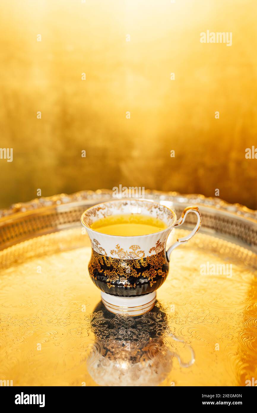 vintage white, black teacup with gold floral design with yellow saffron