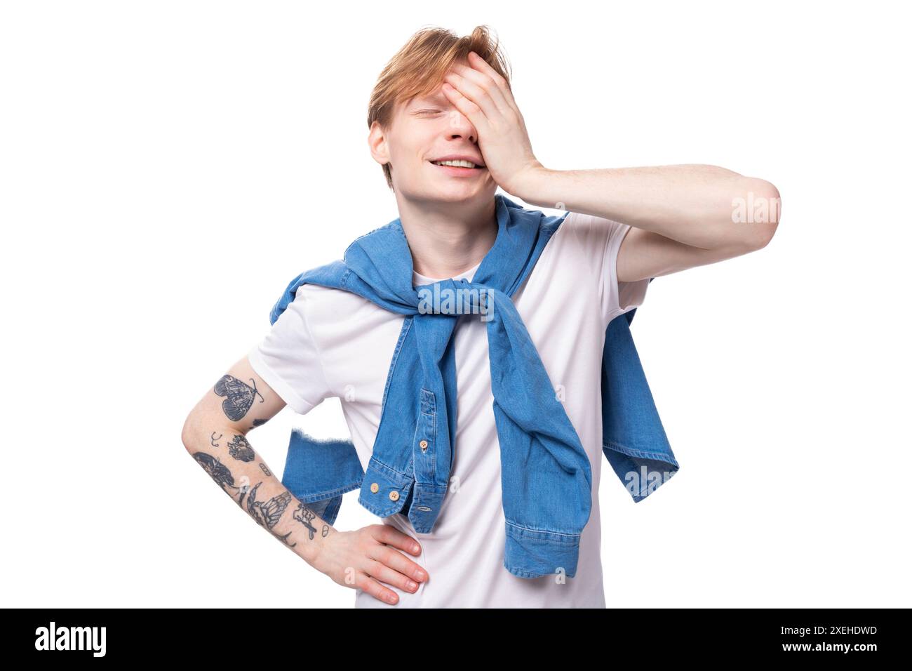 Young positive red-haired man with a short haircut with a tattoo on his arms wearing a white t-shirt Stock Photo