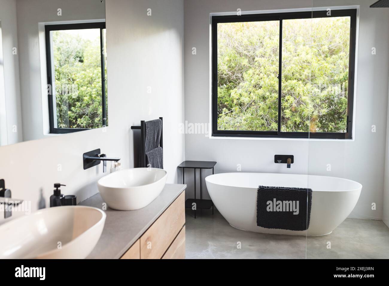 Modern bathroom with freestanding bathtub, double sinks, and large window, copy space Stock Photo