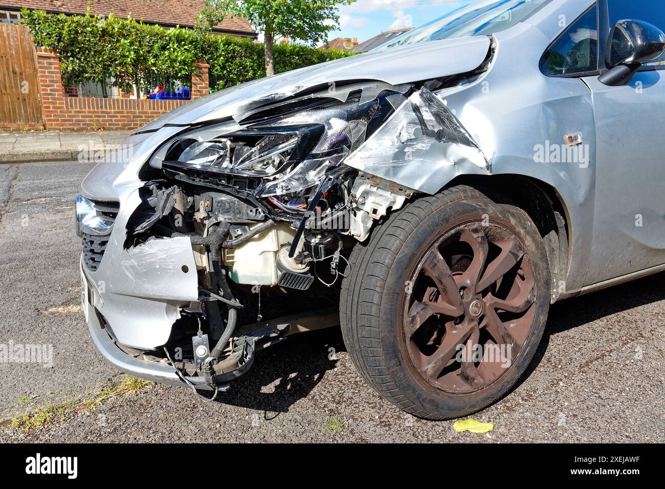 A badly damaged nearside front wing of a small salon car exposing the working parts of the car