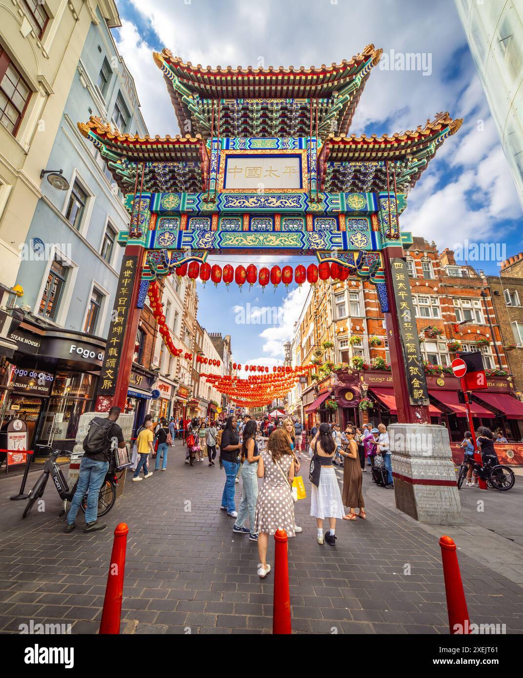 London, United Kingdom - June 25, 2024: Vibrant Chinatown street with traditional archway, lively people and festive lanterns. Stock Photo