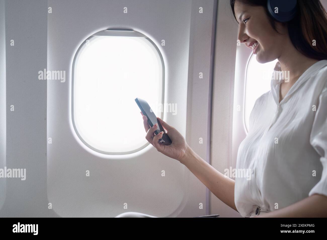 Modern Technology in Flight Travel, Passenger Using Smartphone on Airplane Stock Photo
