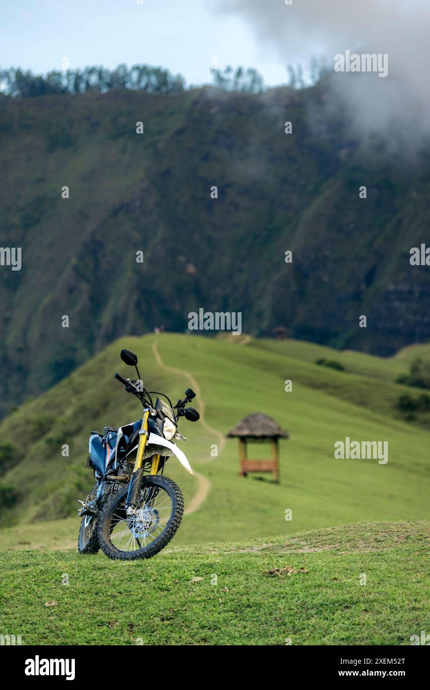 Motorbike parked along a path on a ridge overlooking a rugged ...