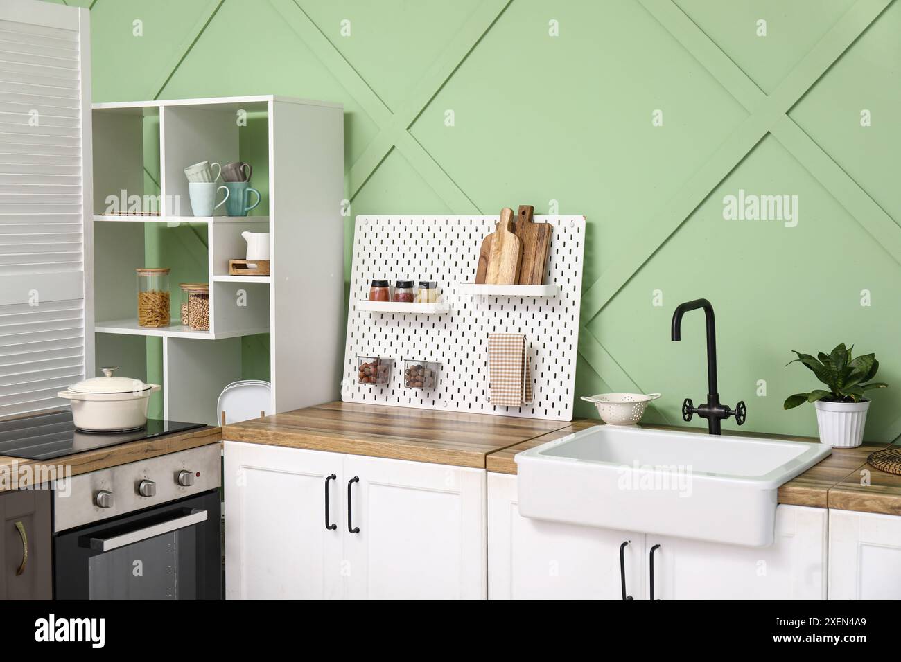 Pegboard, white counters and rack near green wall in interior of modern ...