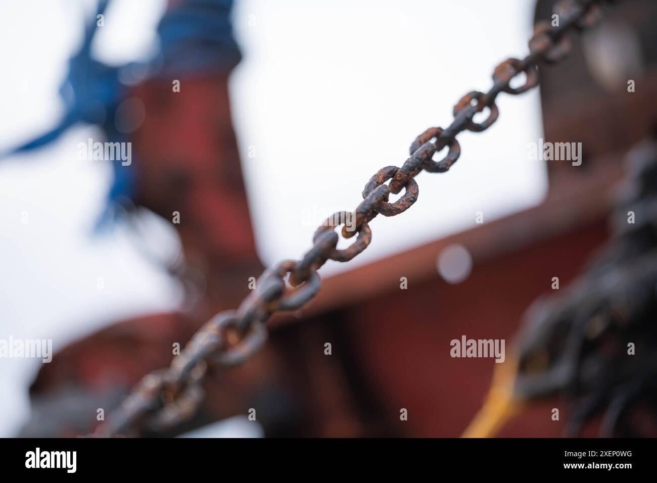 Close-up of a rusty chain with a blurred background, showing signs of wear and age. Stock Photo