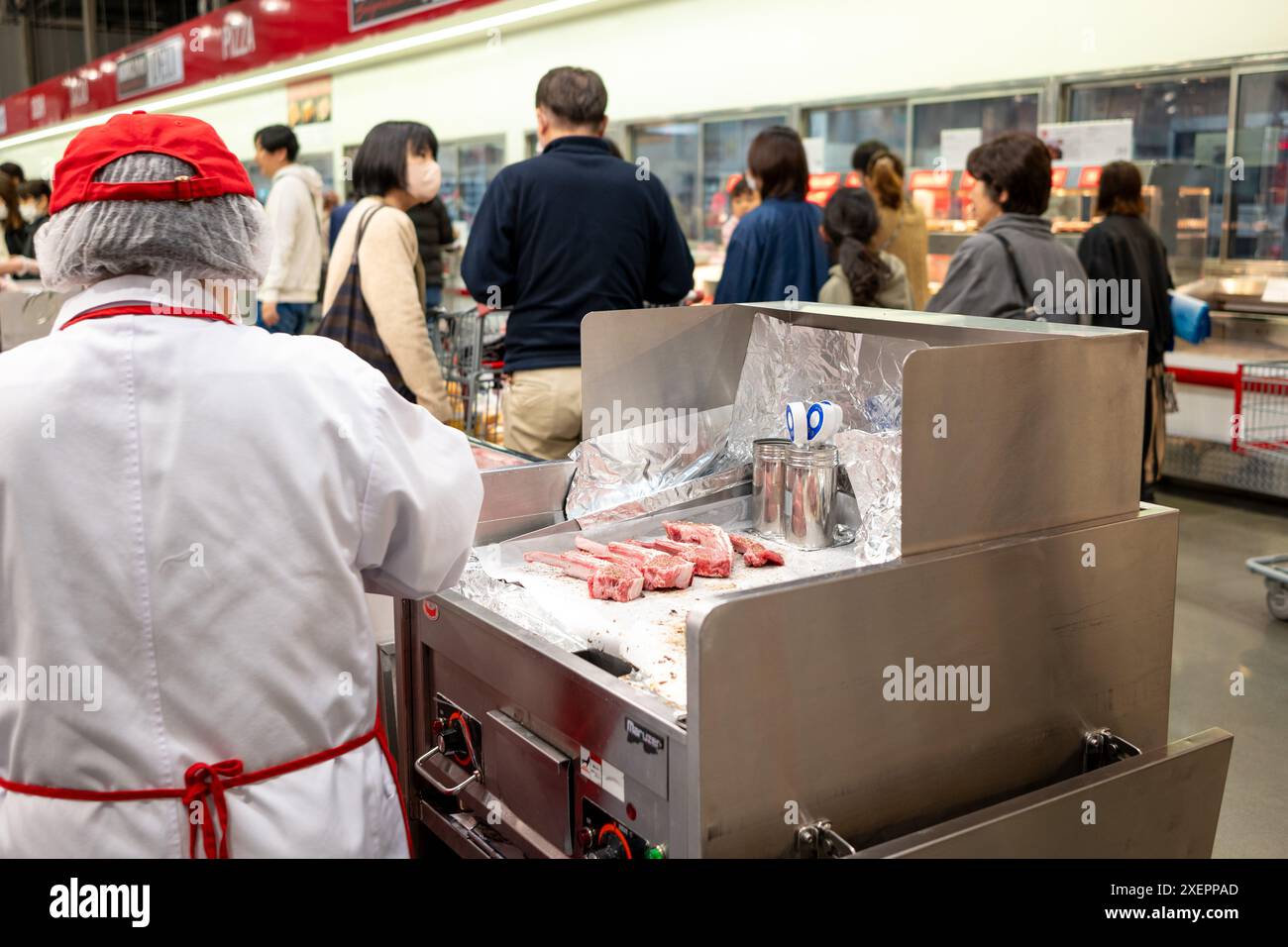 Costco Japan staff prepares meat for free tasting. Stock Photo