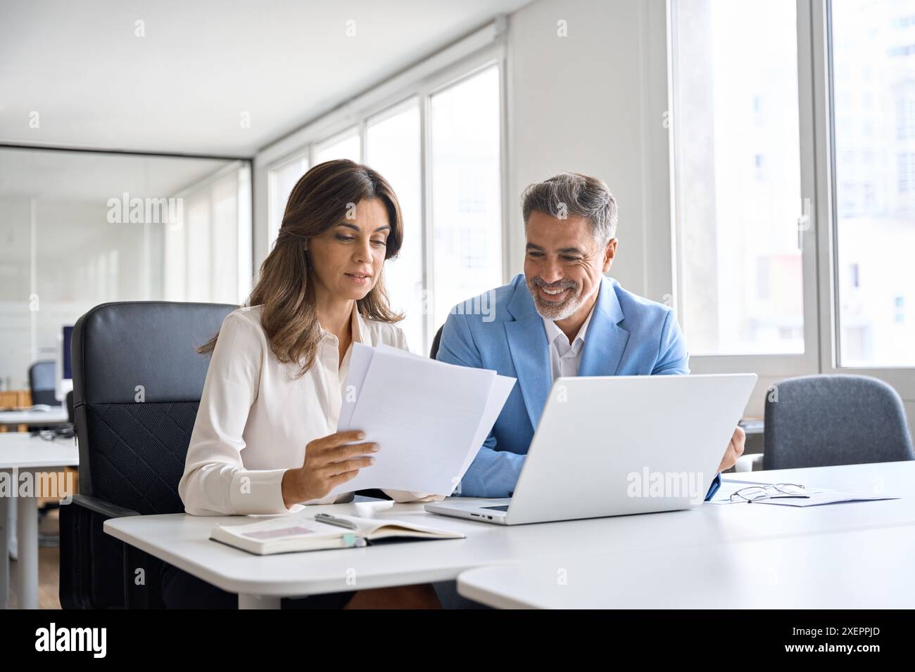 Two executives team working on laptop discussing documents at office meeting. Stock Photo