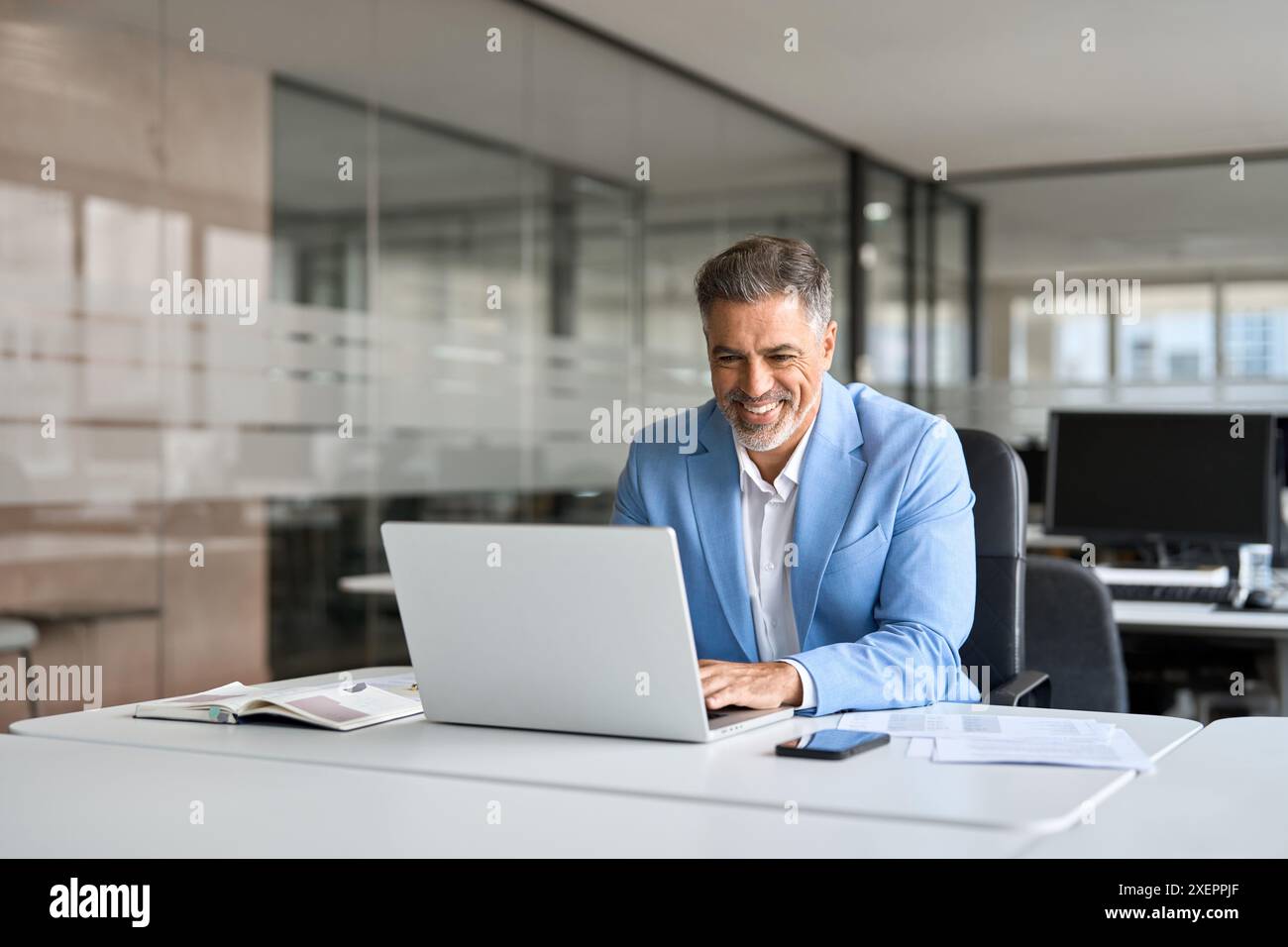 Happy senior older professional business man using computer working at desk. Stock Photo