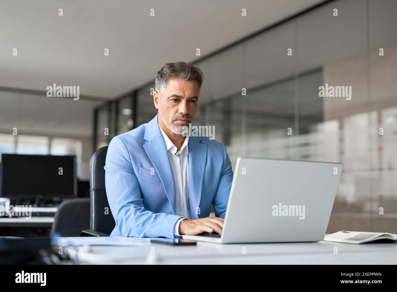 Focused busy middle aged professional business man using laptop in office. Stock Photo