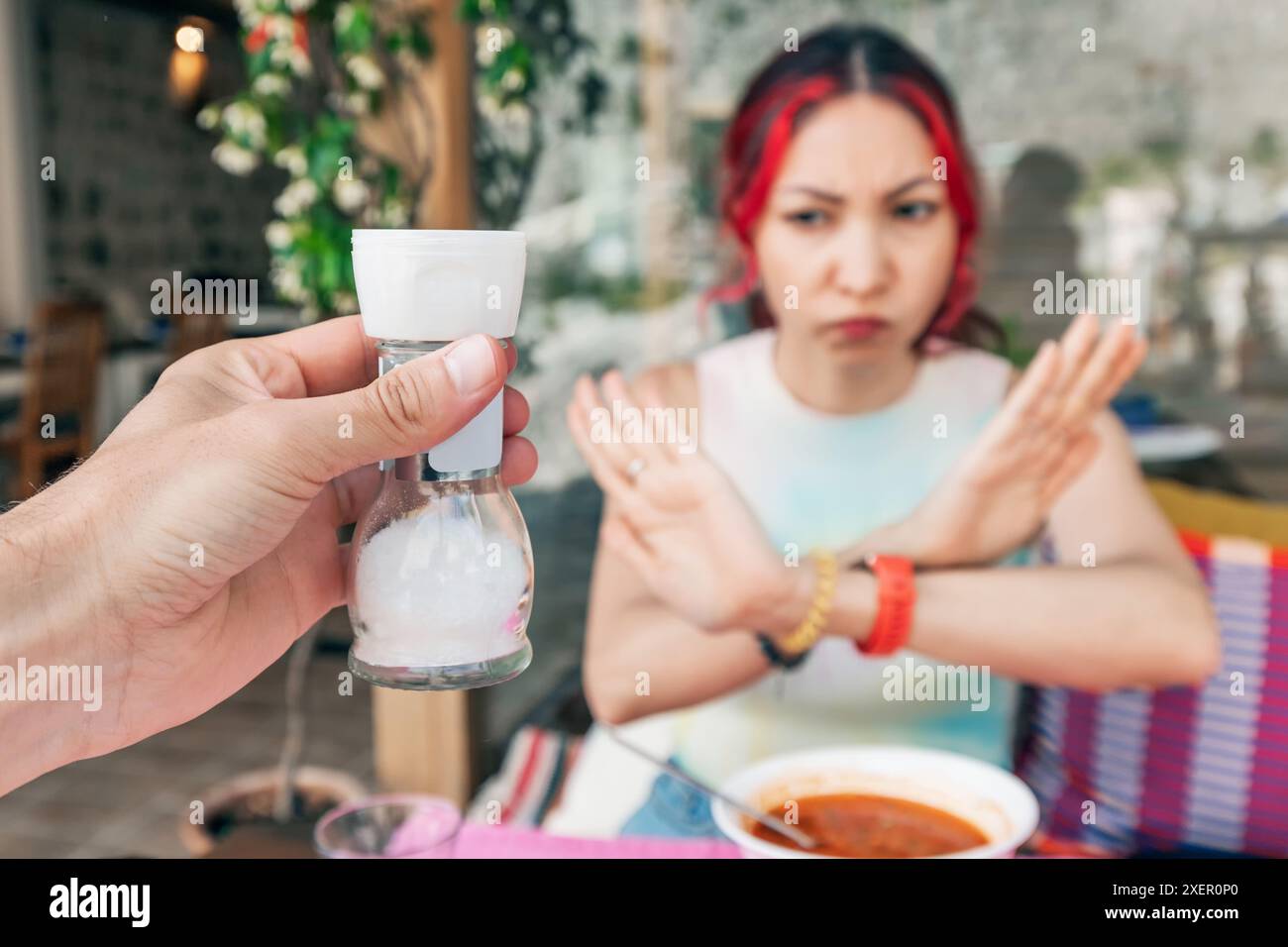Woman Using Salt A hand is holding a salt shaker and woman is refused of adding salt to ...