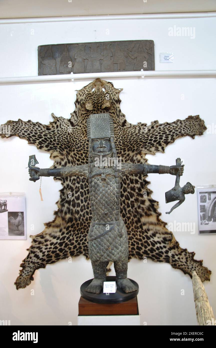Statue of Soldier from Benin Empire, National Museum, Lome, Togo - soldier has various symbols in his hands and an animal skin on the wall behind him. Stock Photo